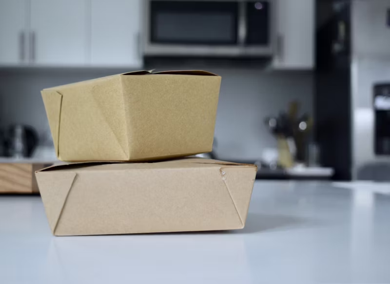 Two stacked eco-friendly takeout boxes on an office kitchen counter