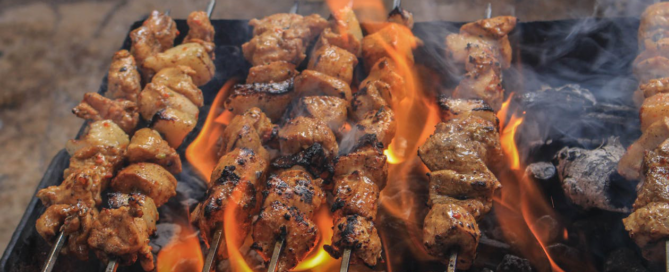 A delicious BBQ platter with ribs, sausage, and sides served on a wooden board.